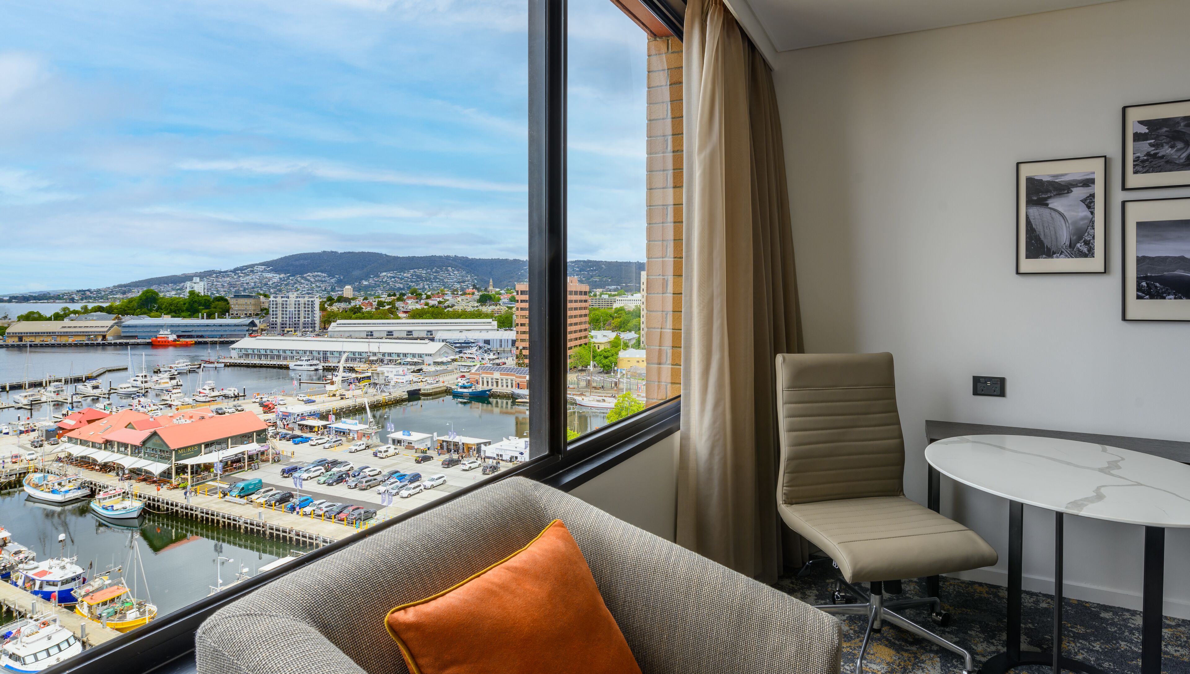 A hotel room with a large window overlooking a marina and cityscape.