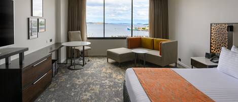 Habitación de hotel con cama, escritorio, silla, una mesita y vista al mar.