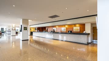 A modern reception area with a polished granite counter, framed artwork, and a clean, reflective floor.