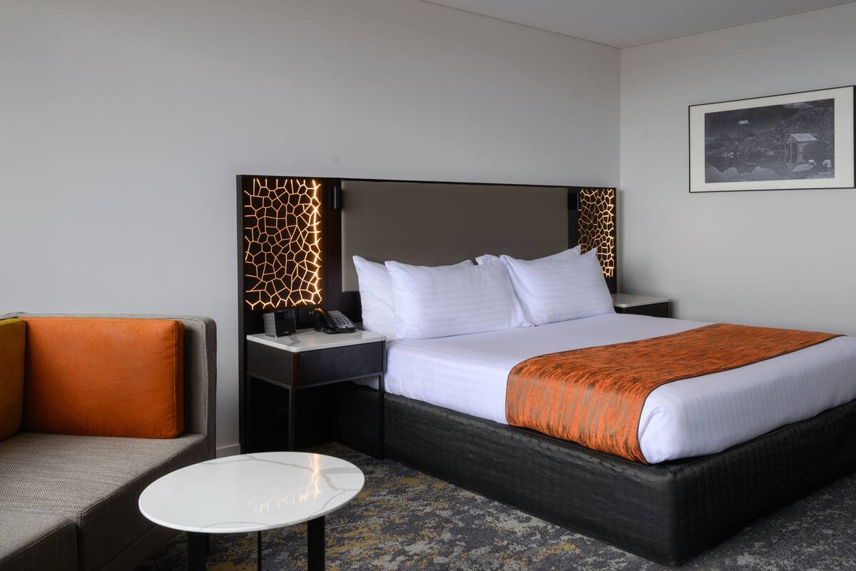Une chambre d’hôtel avec un lit, un bureau, une chaise et une petite table.
