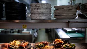 A kitchen counter with stacked plates and bowls of food.
