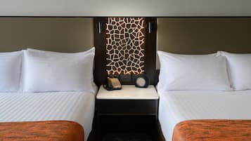 Habitación de hotel con dos camas, una mesita de noche con teléfono y un panel decorativo en la pared.