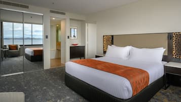 A hotel room with a large bed, a desk, a chair, and a view of the water.