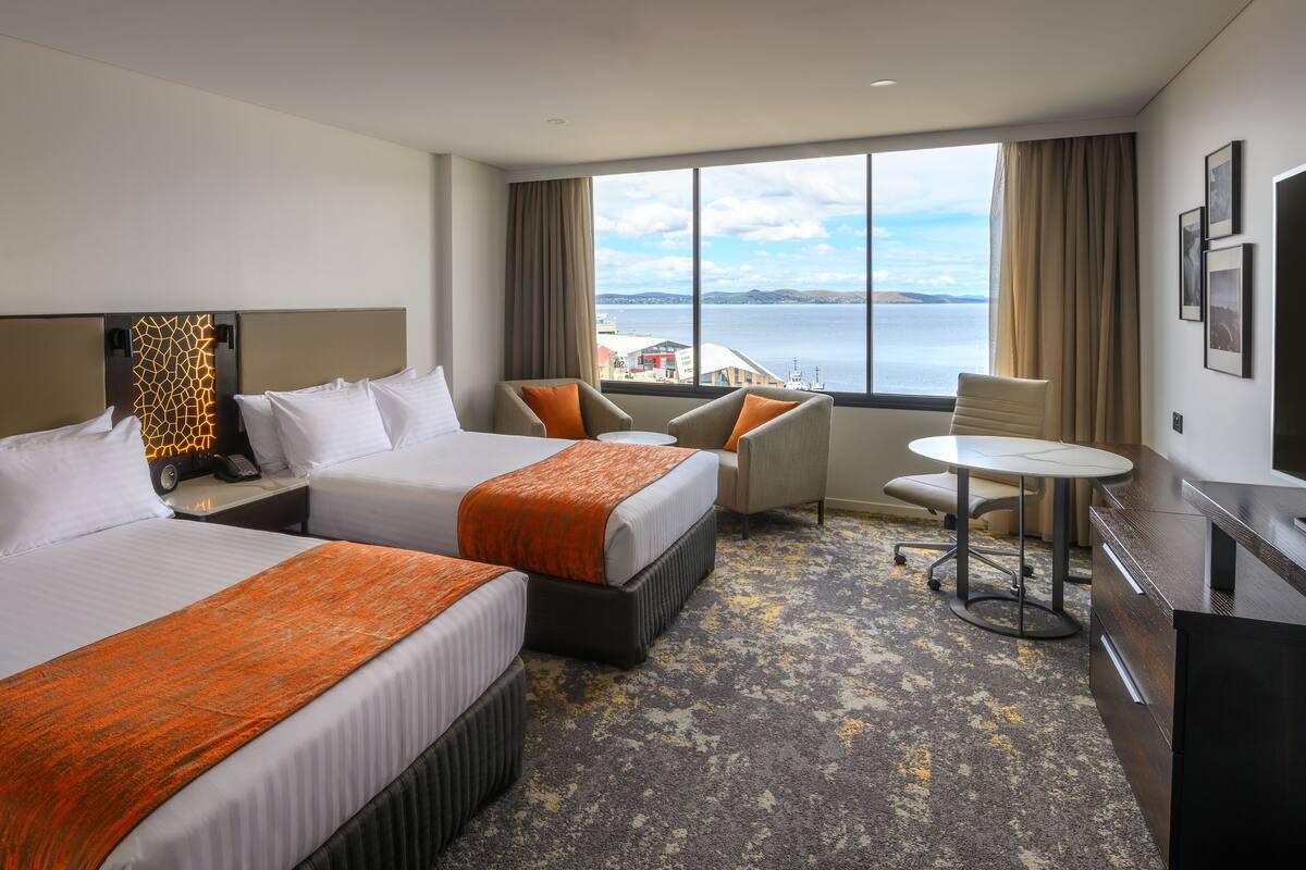 Une chambre d’hôtel avec deux lits, un bureau, une chaise et une vue sur la mer.