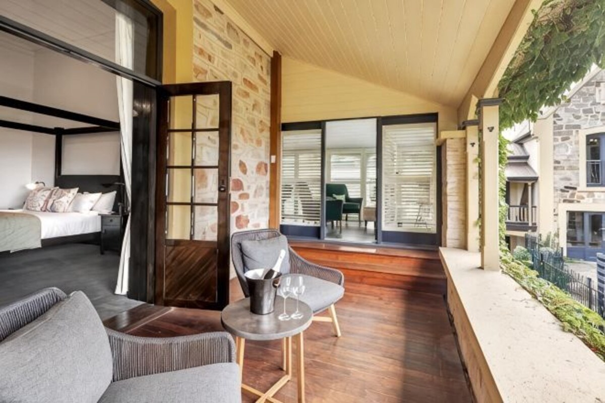 A modern room with a bed, a seating area with a table and chairs, and a view of the outside.