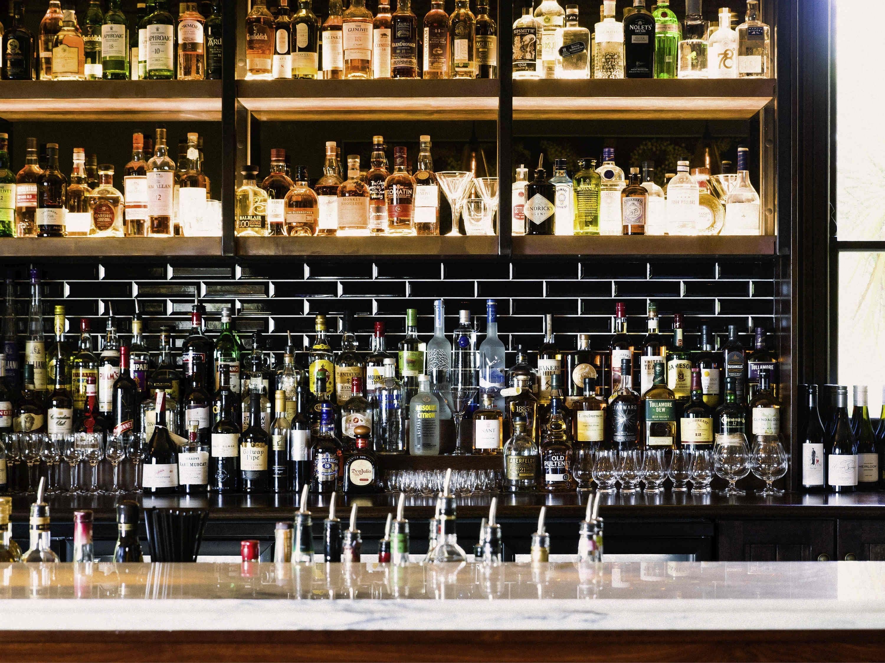 A bar with multiple shelves of liquor bottles and glasses.