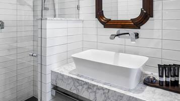 A modern bathroom with a large mirror, white tiles, a freestanding bathtub, and a shower area.