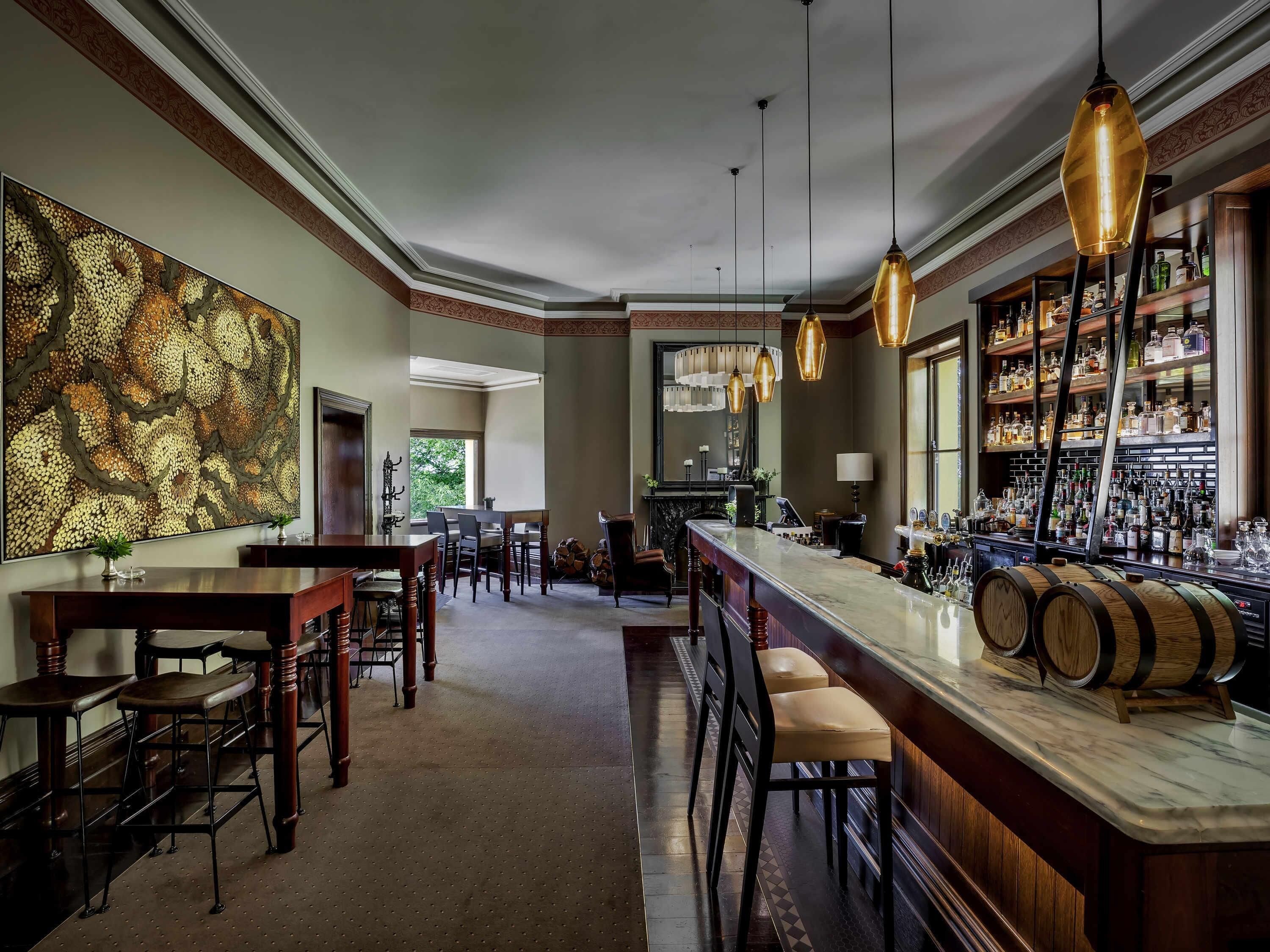 Zona de bar con encimera de mármol, sillas de madera y una estantería para vinos.