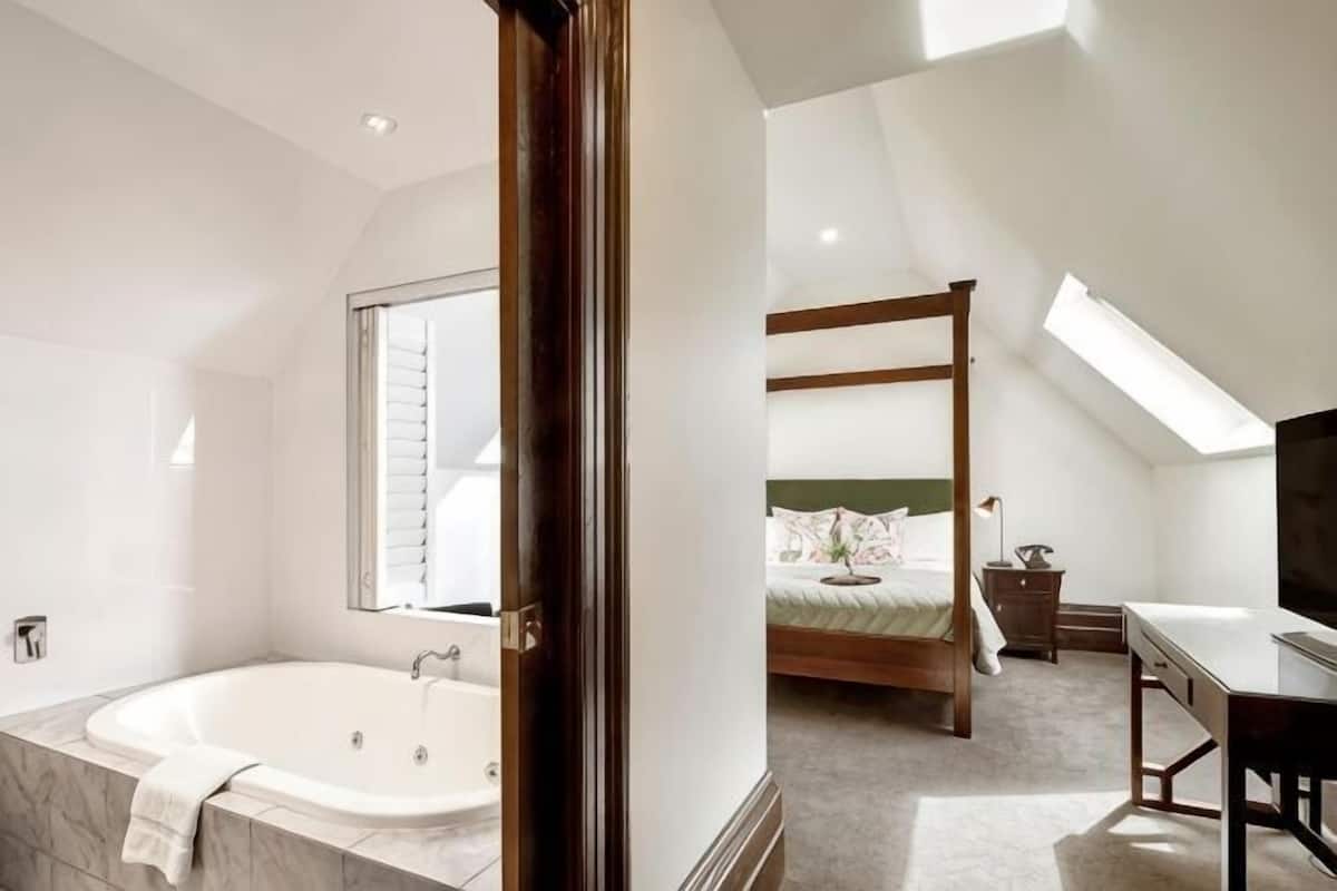 A bedroom with a four-poster bed, a skylight, and a large window.