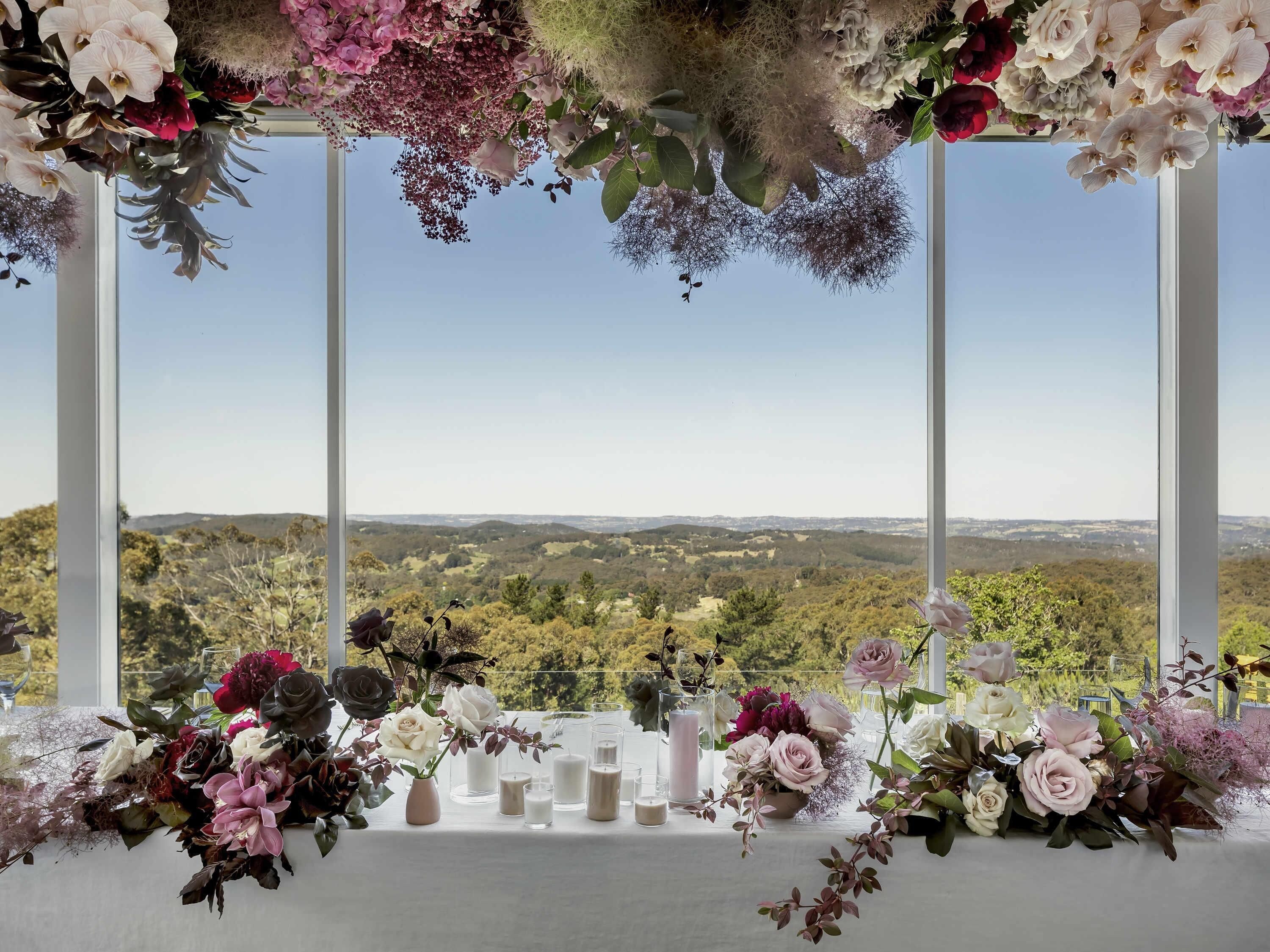Ein Tisch, gedeckt mit Blumen und Kerzen, mit Blick auf eine malerische Landschaft.