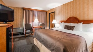 A hotel room with a bed, a TV, a desk, two chairs, a lamp, and a nightstand. - Best Western Pendleton Inn (Pendleton)