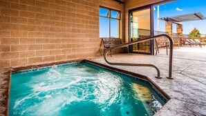 A swimming pool with a metal ladder, a brick wall, and a glass door leading to an outdoor seating area. - Best Western Pendleton Inn (Pendleton)