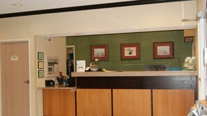 Un espace d’accueil avec un comptoir en bois, des tableaux encadrés accrochés au mur et une porte portant l’inscription « Réservé au personnel ».