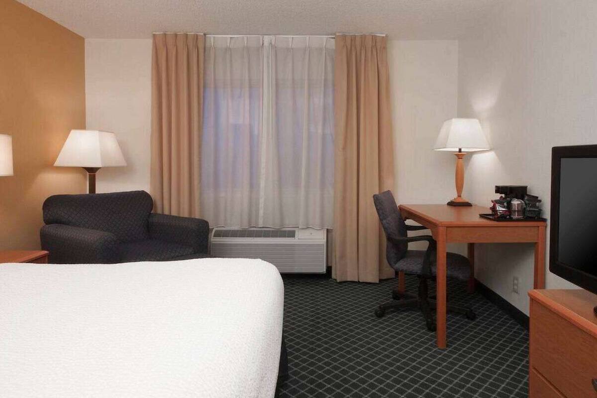 Une chambre d’hôtel équipée d’un lit, d’un bureau, d’une chaise, d’une télévision et d’un appareil de climatisation.