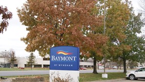 Une enseigne de l’hôtel Baymont by Wyndham, avec un parking et des arbres en arrière-plan.