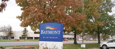 A sign for Baymont by Wyndham with a parking lot and trees in the background.