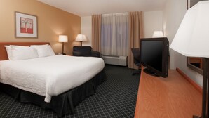 Une chambre d’hôtel avec un grand lit, deux lampes de chevet, un téléviseur à écran plat, une fenêtre avec des rideaux et un tableau encadré au mur.