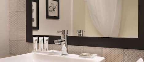 Un baño moderno con un lavamanos grande, un espejo y una obra de arte enmarcada en la pared.