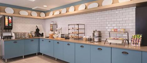A modern kitchen with blue cabinets, white subway tiles, and a variety of appliances and utensils.