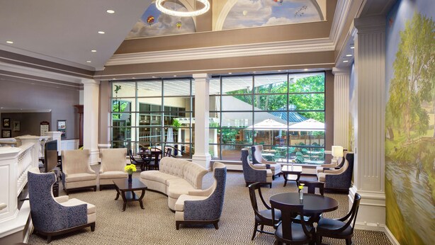 A spacious lobby with a large seating area, a reception desk, and a view of the outdoors through large windows. - Desmond Hotel Malvern, a DoubleTree by Hilton (Malvern)