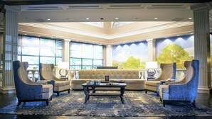 A spacious lobby with a large sofa, two armchairs, a coffee table, and a large window with a view of greenery. - Desmond Hotel Malvern, a DoubleTree by Hilton (Malvern)