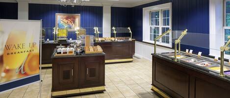 A buffet area with multiple food stations, a sign for breakfast, and a chandelier.