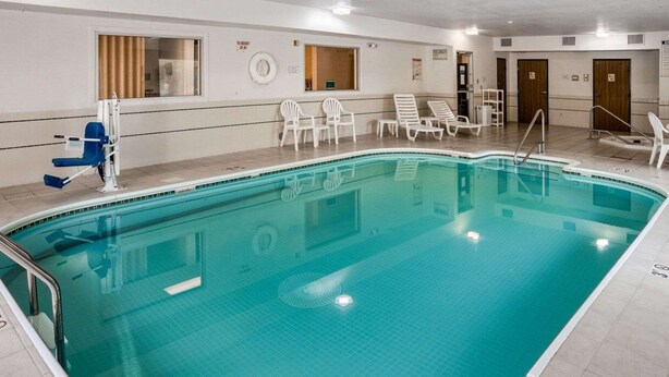 A swimming pool with a tiled deck, lounge chairs, and a changing room.