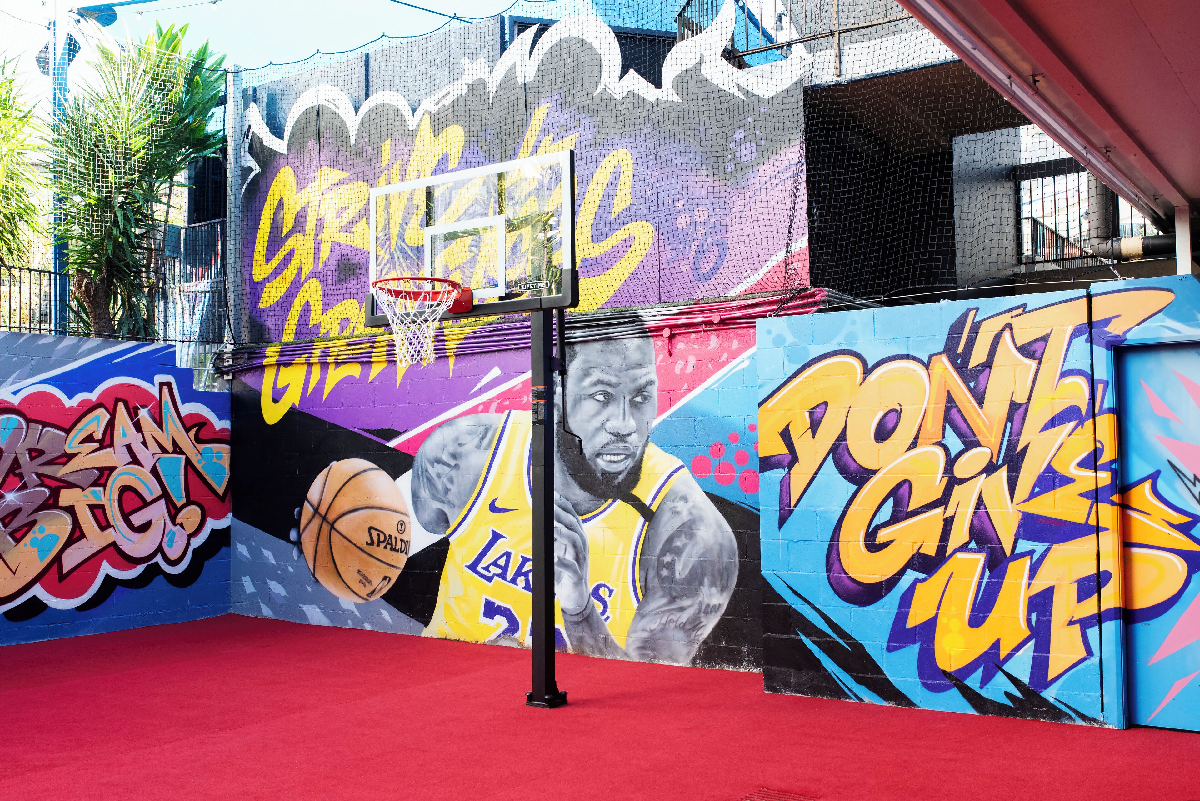A basketball court with graffiti art and a basketball hoop.