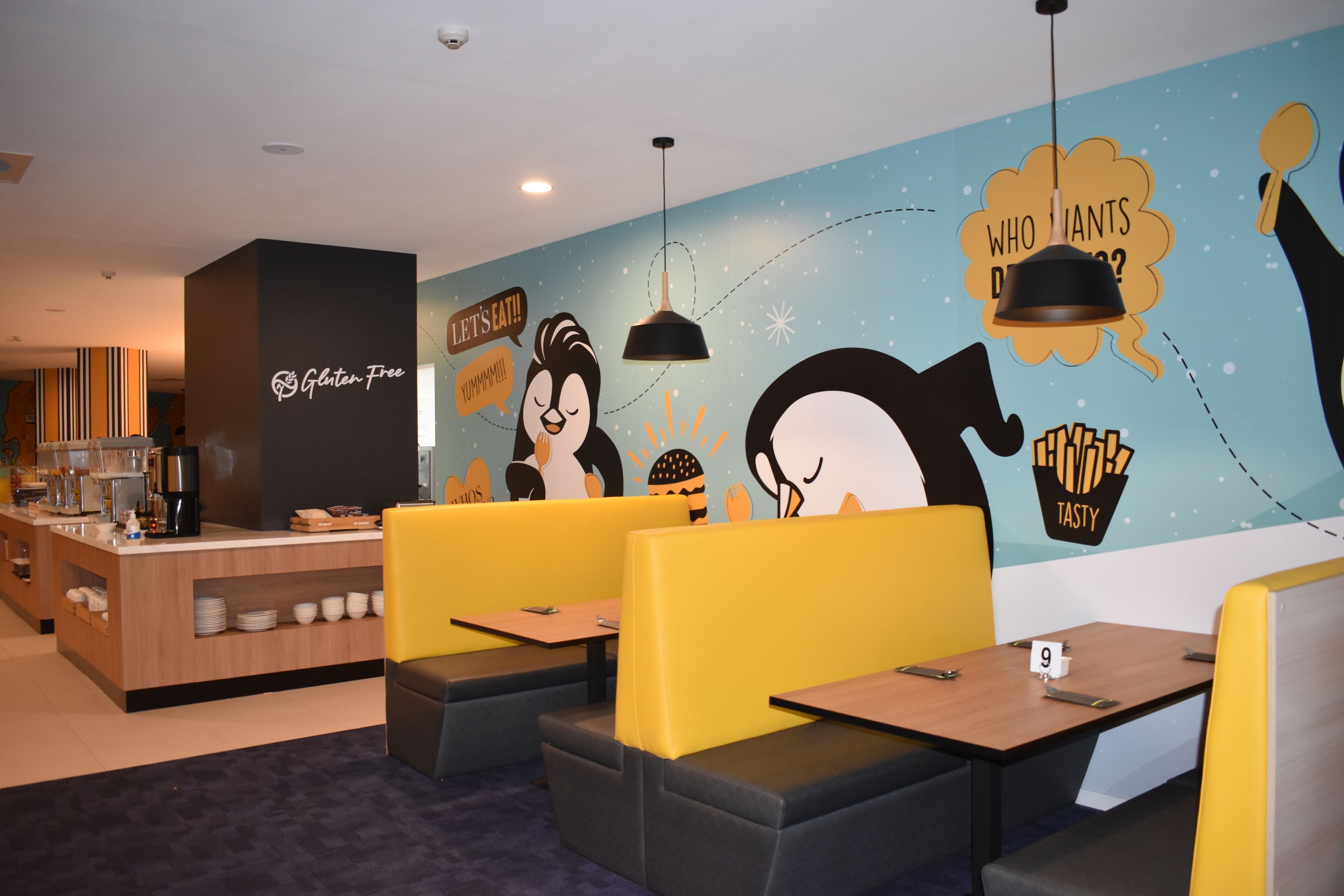 A restaurant with a gluten-free sign, cartoon characters, and a counter with coffee machines.