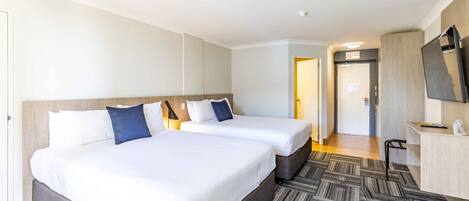 A hotel room with two beds, a desk, and a television.