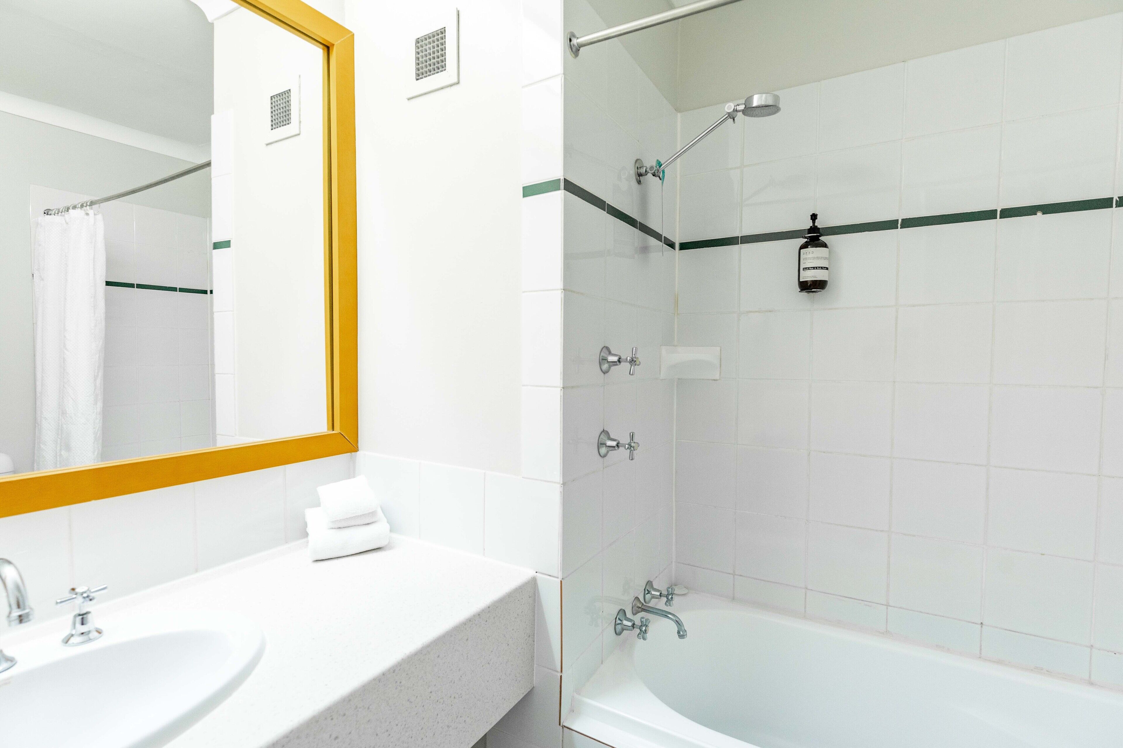 A bathroom with a sink, mirror, and shower.