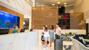 A reception area with a marble counter, a large aquarium, and a play area with colorful play structures. - Paradise Resort Gold Coast (Surfers Paradise)