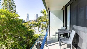 A balcony with a table and chairs, overlooking a parking area and buildings. - Paradise Resort Gold Coast (Surfers Paradise)