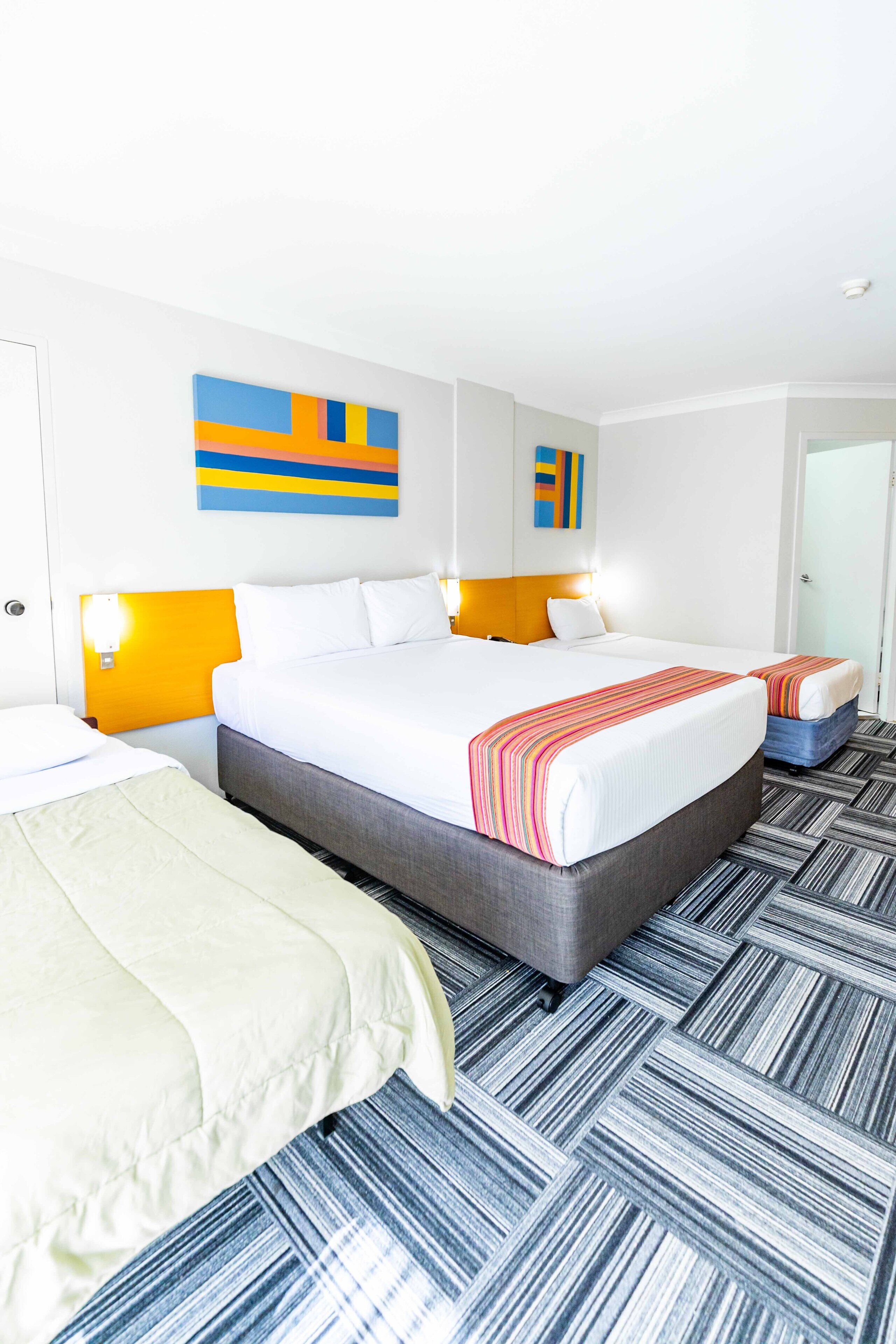 Una habitación de hotel con una cama grande, dos mesitas de noche y una puerta.