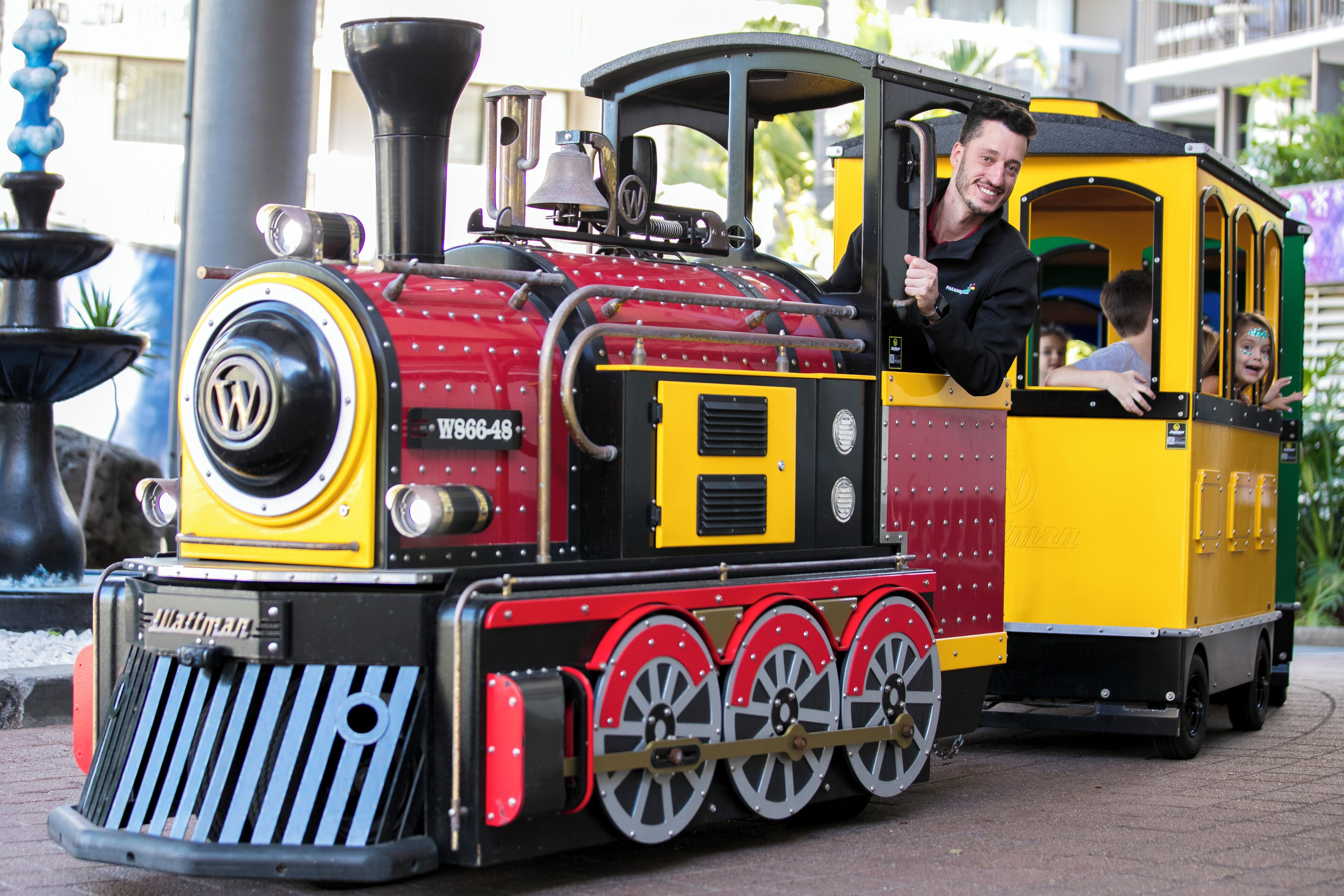A miniature train with a black and yellow color scheme, a visible logo, and a bell on top.