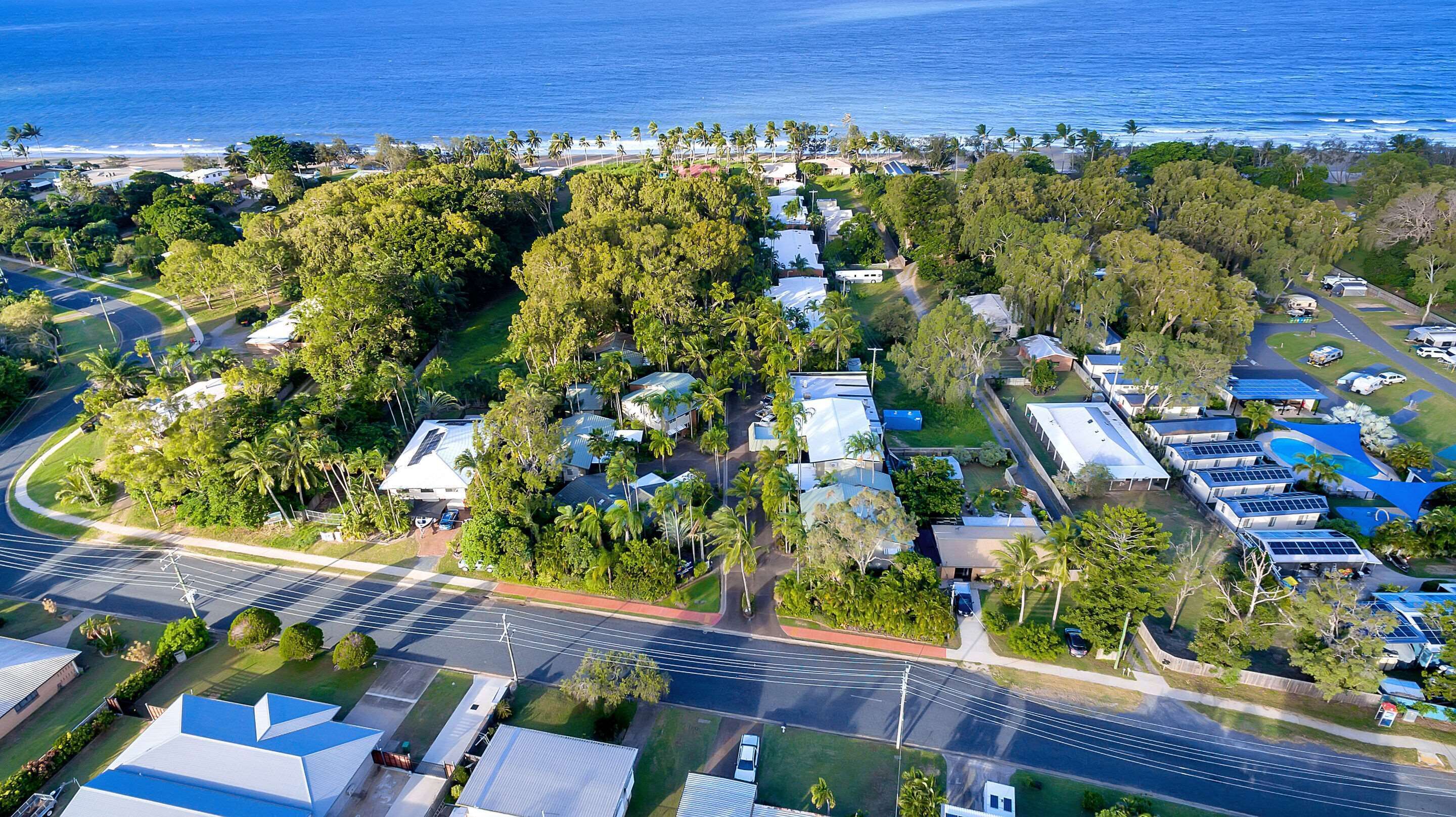 An aerial view of a residential area with houses, roads, and a beach in the background.