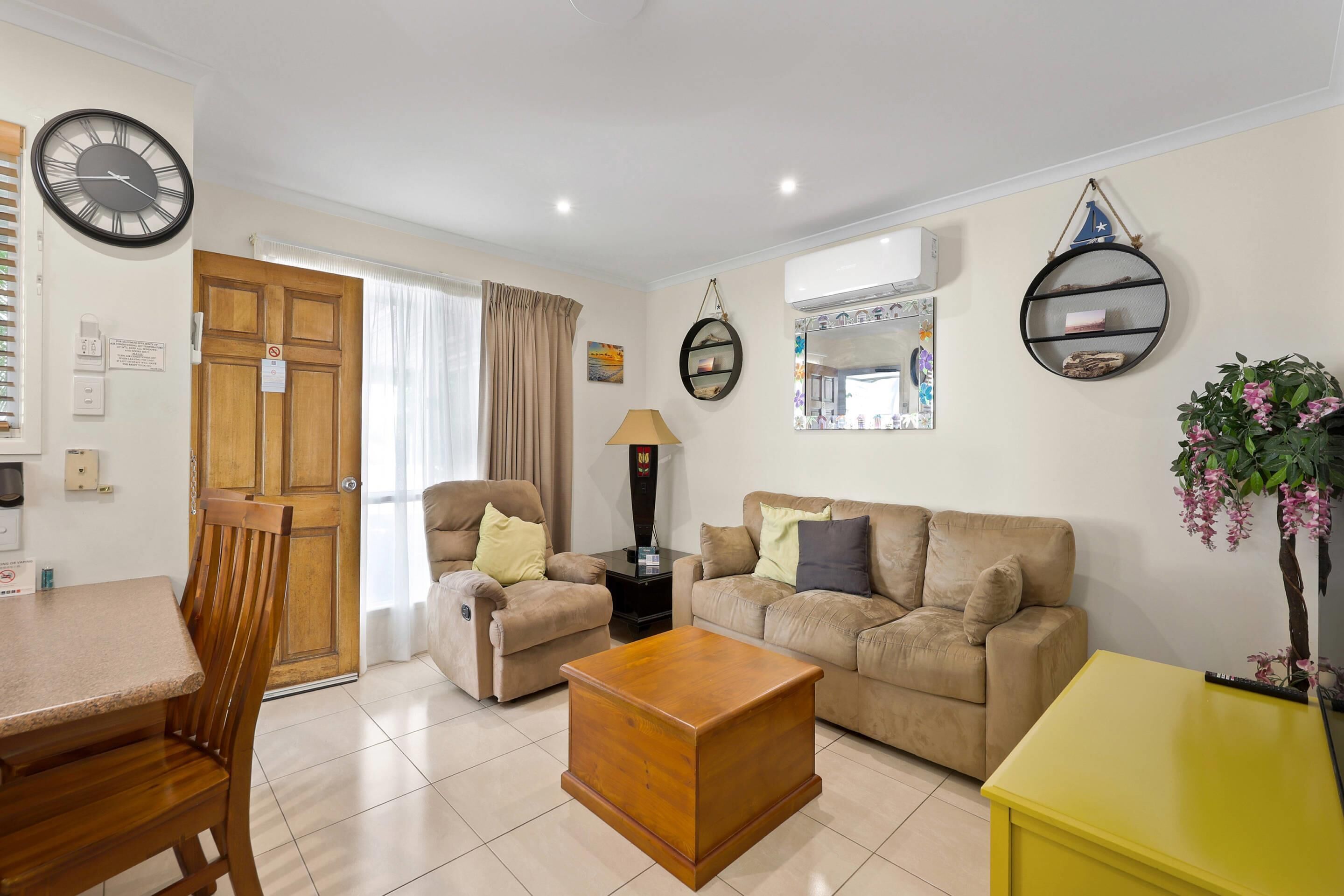 A living room with a wooden dining table, two sofas, a coffee table, and a yellow side table.
