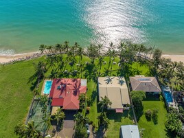 Vista aérea de una propiedad costera con piscina, dos casas y una playa.