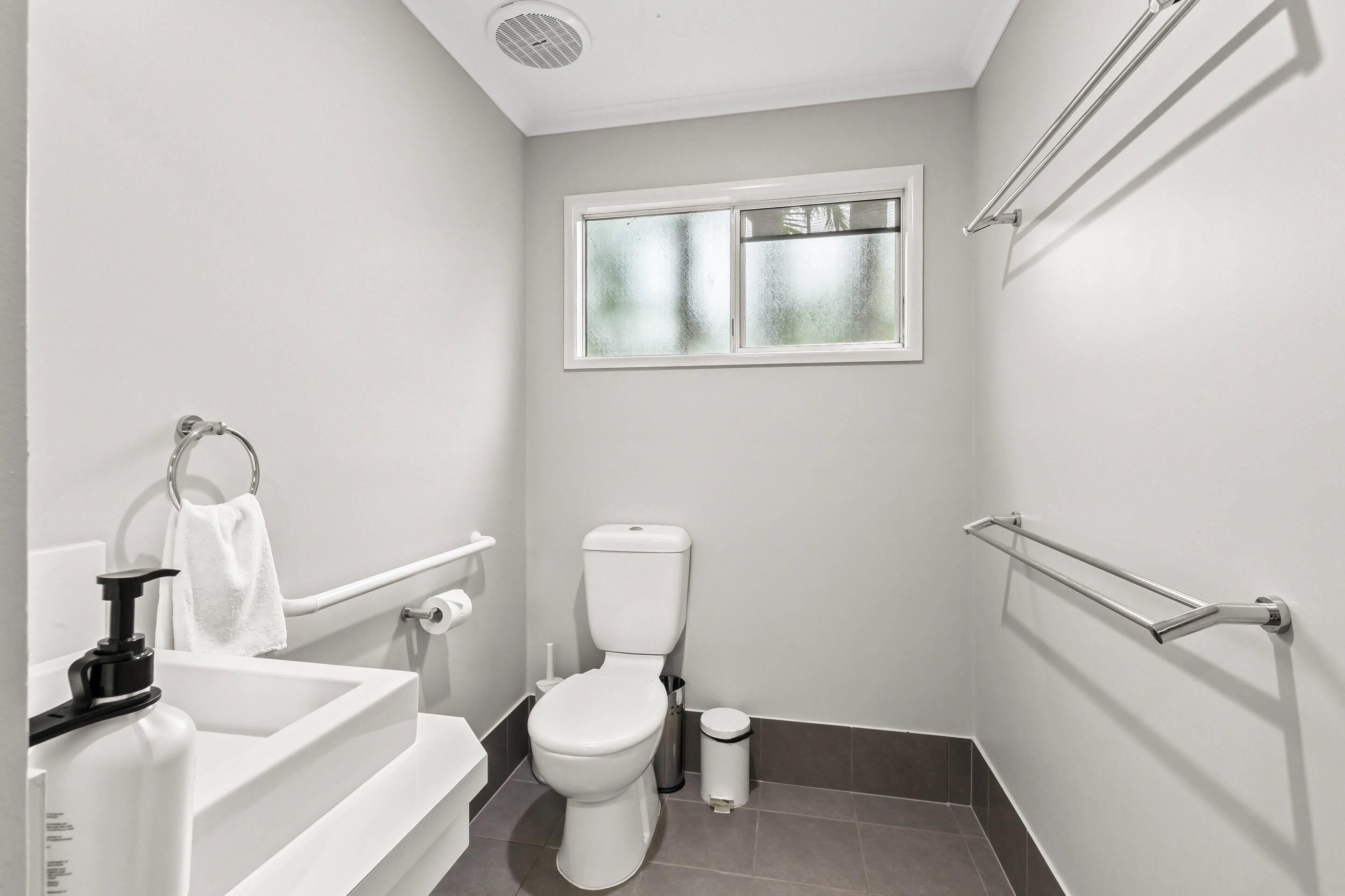 Un baño pequeño y moderno con inodoro, lavamanos y ventana.