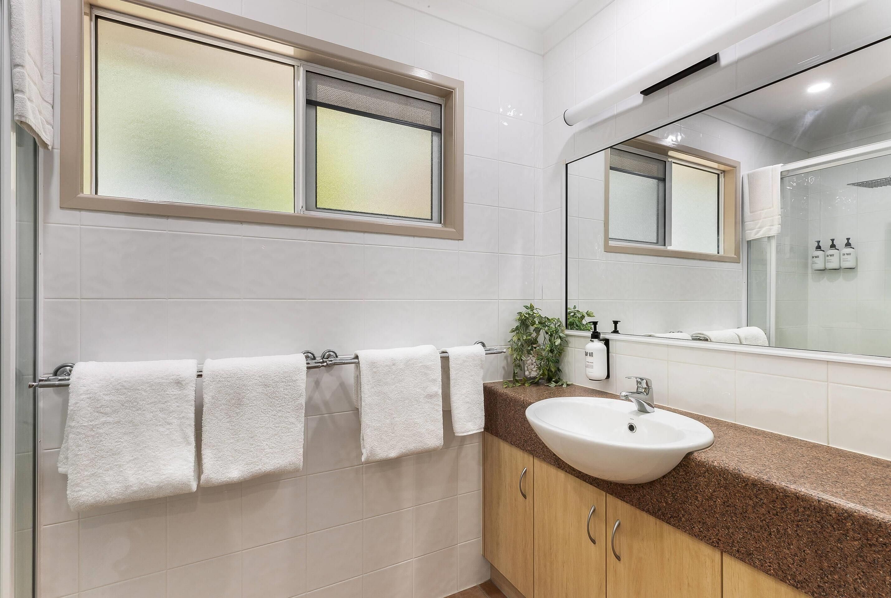 Une salle de bain moderne avec un grand miroir, un lavabo et un porte-serviettes.