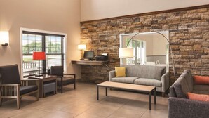 A spacious living area with a stone accent wall, a flat-screen TV, and a comfortable seating arrangement. - Country Inn & Suites by Radisson, Buffalo, MN (Buffalo)