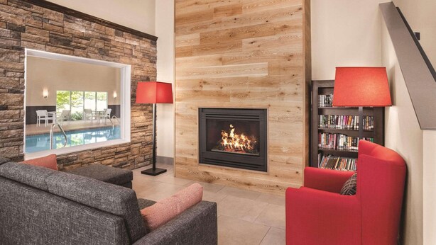 A modern living room with a fireplace, a pool view, and a bookshelf. - Country Inn & Suites by Radisson, Buffalo, MN (Buffalo)