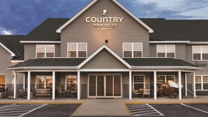 A Country Inn & Suites by Radisson building with a covered front porch, large windows, and a parking lot. - Country Inn & Suites by Radisson, Buffalo, MN (Buffalo)