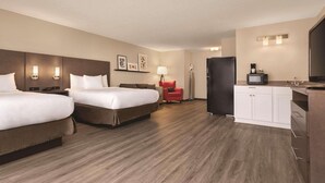 A hotel room with two beds, a red chair, a kitchenette, and a TV. - Country Inn & Suites by Radisson, Buffalo, MN (Buffalo)