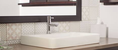 A bathroom with a white sink, a chrome faucet, and a mirror above it.