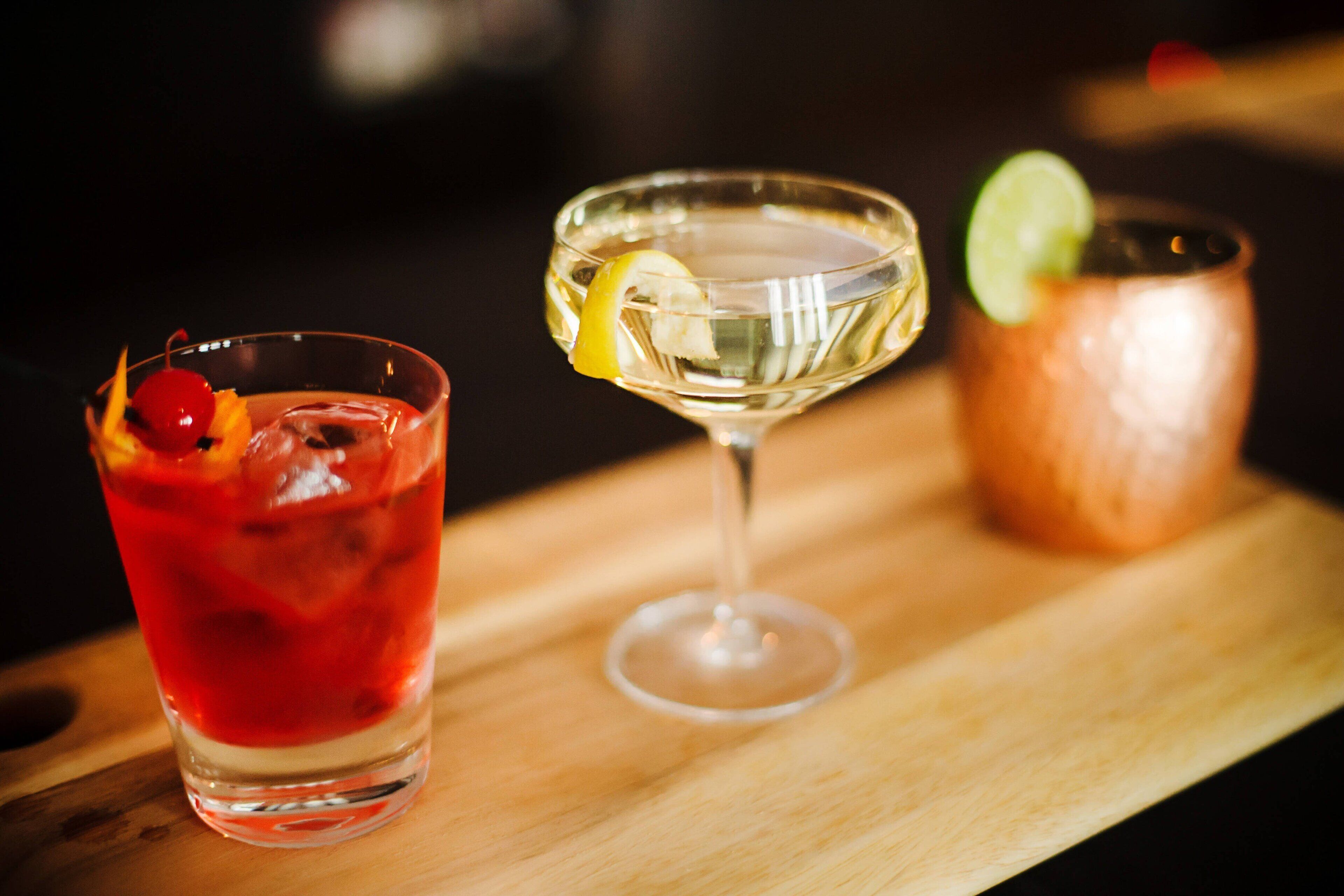 Two cocktails on a wooden tray.