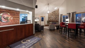 En hotellobby med en receptionsdisk i trä, en öppen spis i sten och en bar med sittplatser.