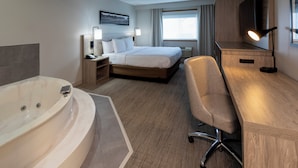 Ett hotellrum med ett stort badkar, en säng, ett skrivbord och en tv.