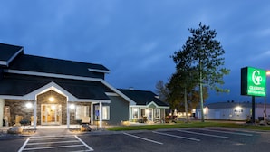 Ett GrandStay Hotel & Suites med en fasad av sten, en parkeringsplats och en stor skylt.