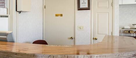 A reception desk with a wooden top, a sign prohibiting pets, and a 'No Smoking' sign on the wall.